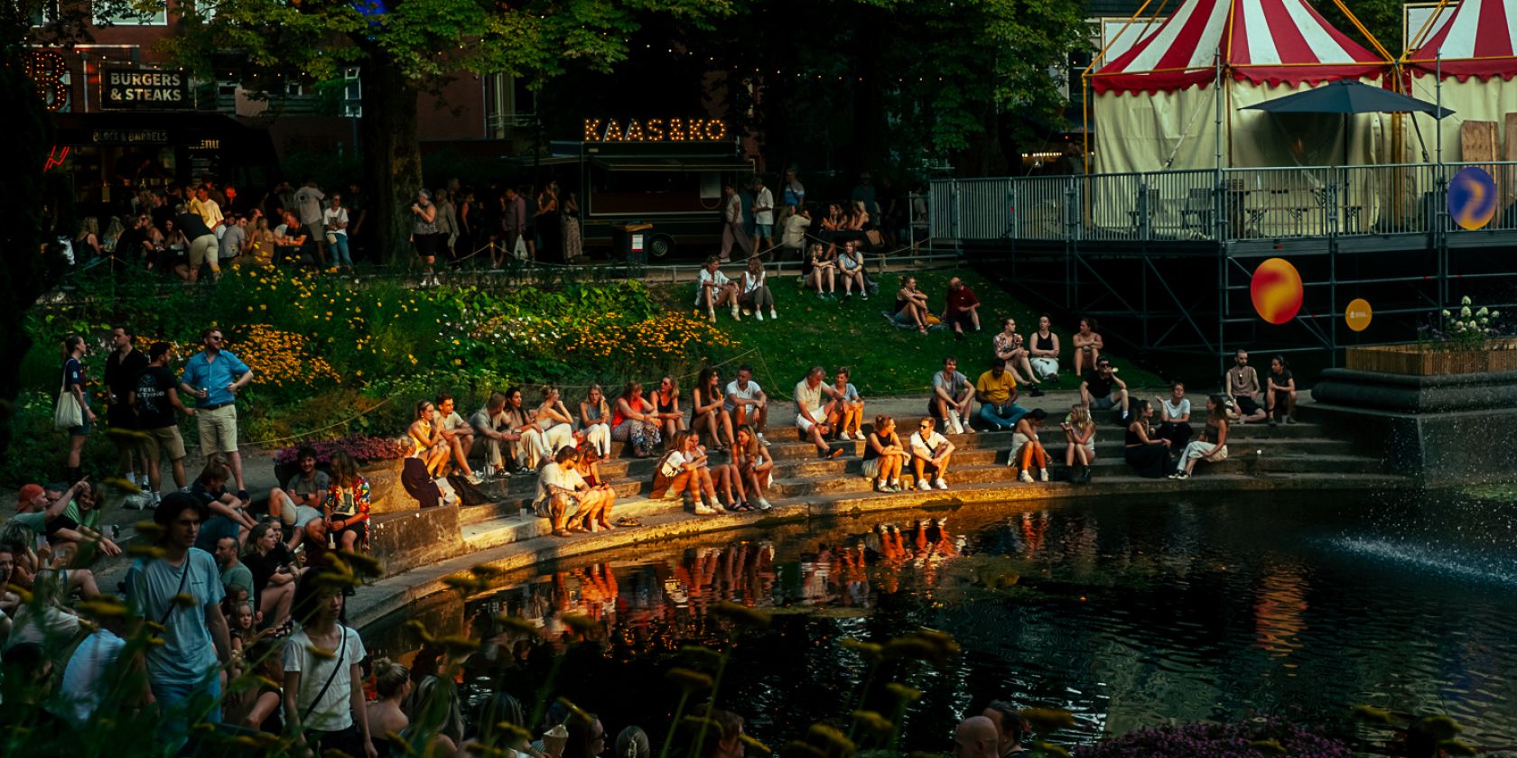 Mensen verzameld bij een vijver op een zomerfestival in Groningen